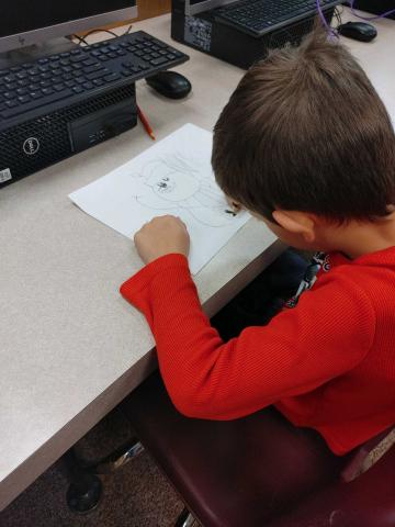 kindergartener coloring his finished drawing.