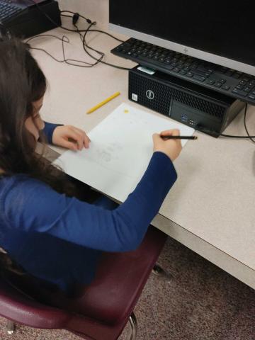 kindergartener working on coloring her art paper.