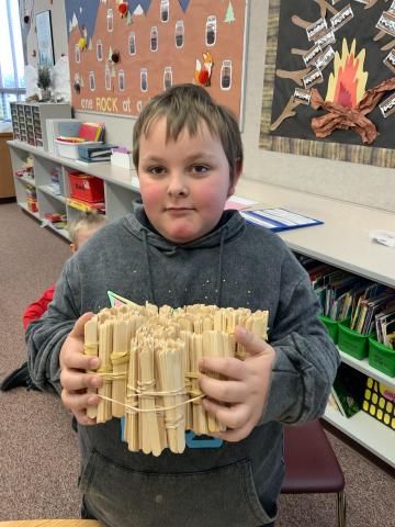 2md Grader showing just how big 1,000 craft sticks are
