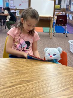 Girl reading to her teddy bear